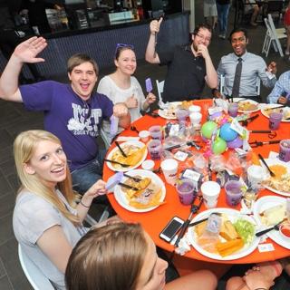 A group of TCU students raise 的ir celebratory purple margaritas at a festive round table